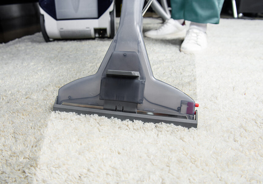 cropped shot of person cleaning white carpet with professional vacuum cleaner